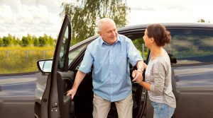 Carer helping elderly man out of car