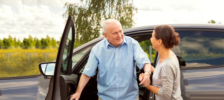 Carer helping elderly man out of car