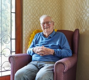 Male Home Care Package client sitting in an armchair and smiling