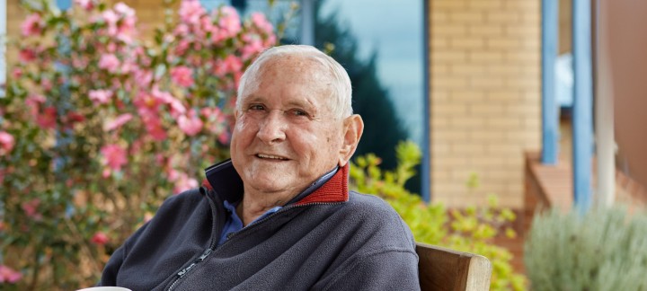 Male Home Care Package client sitting outside with a cup and smiling