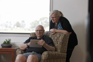 Female carer helping male client with his iPad