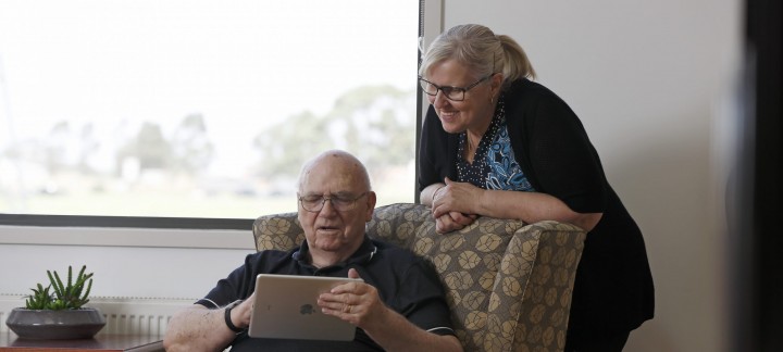 Female carer helping male client with his iPad