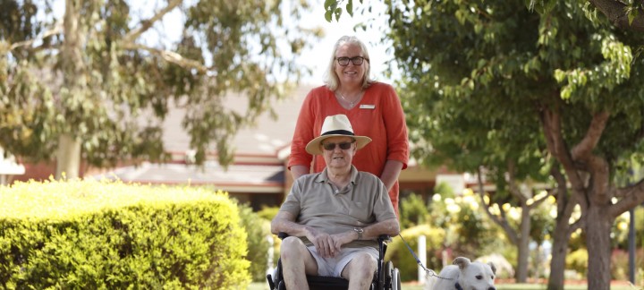 Carer pushing a male client in wheelchair with white dog in Shepparton