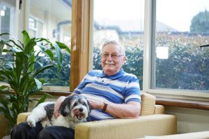 male client enjoying feeding his black and white dog some treats
