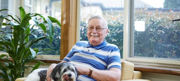 male client enjoying feeding his black and white dog some treats