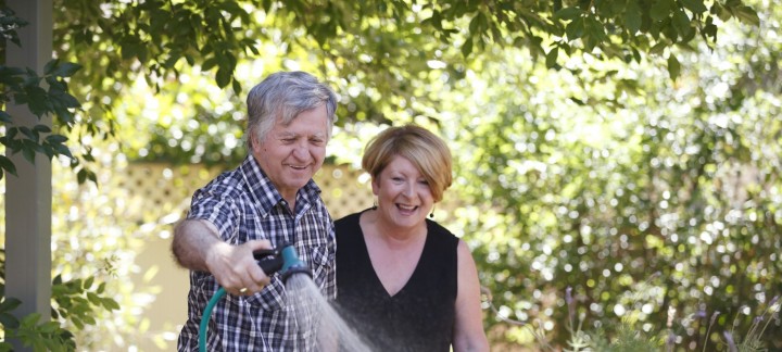 Female home care worker helping male Home Care Package client to water his garden
